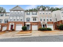 Three-story townhouses with brick and siding, two-car garages, and landscaping at 3944 Howell Park Rd, Duluth, GA 30096