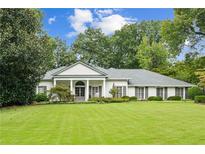 Beautiful white brick home with a manicured lawn and mature trees at 5915 Riverwood Dr, Atlanta, GA 30328