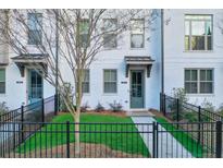 Charming townhome featuring a white brick facade, a well-manicured lawn, and a secure black metal fence at 2893 Elmwood Se Dr, Smyrna, GA 30080