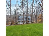 Two-story house with gray siding, white porch, and grassy yard nestled among trees at 818 Victoria Pl, Woodstock, GA 30189