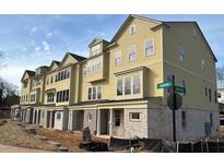 Newly constructed townhomes featuring yellow siding, brick accents, and visible street signs at 1980 Flying Scotsman Dr # 10, Kennesaw, GA 30144