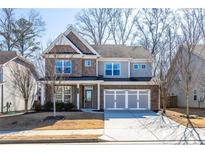 Traditional two-story home featuring a brick and siding facade, well-manicured lawn, and an attached three-car garage at 333 Gardens Of Harmony Dr, Canton, GA 30115