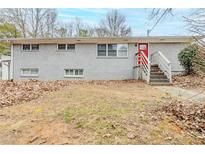 Modest two-story home featuring a red door, painted brick, mature trees, and front yard at 250 Hermer Nw Cir, Atlanta, GA 30311