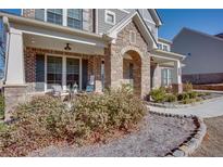 Charming front porch featuring stone accents, outdoor seating, and manicured landscaping at 5015 Montes Ln, Cumming, GA 30040