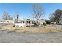 Tan mobile home with a fenced yard, shed, and landscaping at 127 Cambridge Ct, Hampton, GA 30228