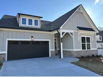 Charming home with a two-car garage, gray siding, black roof and brick foundation, complemented by a well-manicured lawn at 1105 Cooks Farm Way, Woodstock, GA 30189