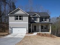 Two story home featuring gray siding, a two-car garage, covered porch, and professional landscaping at 250 Shawnee Trl, Dallas, GA 30157