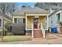 Charming yellow home featuring a welcoming front porch with swing and brick stairs at 725 Oakland Se Ave, Atlanta, GA 30315