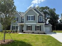 Charming two-story home featuring light gray siding, black shutters, a well-manicured lawn, and an attached garage at 1391 Stephens View Dr, Loganville, GA 30052