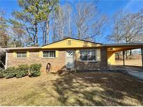 Charming one-story brick home featuring a covered carport and a tidy front yard, perfect for a starter home at 5961 John St, Austell, GA 30106