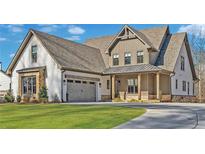 Beautiful two-story home with a manicured lawn, stone accents, and a three-car garage at 102 Creekview Ln, Canton, GA 30115