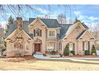 Stunning brick home with a stone chimney, manicured lawn, and a charming outdoor seating area at 4478 Outpost Ct, Roswell, GA 30075