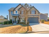 Charming two-story home featuring a stone facade, covered porch, and well-manicured lawn at 115 Greenbrier Way, Canton, GA 30114