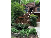 A beautiful entrance with wooden steps accented by flowering planters and verdant landscaping at 3457 Winter Wood Cv, Marietta, GA 30062