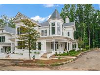 Two-story white house with a wraparound porch and landscaped yard at 11577 Serenbe Ln, Chattahoochee Hills, GA 30268