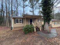 Tan house with black shutters, wooden steps, and landscaping at 6871 Lakeshore Dr, Douglasville, GA 30135