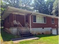 Brick ranch house with a porch and a swing, nestled amongst lush trees at 1230 Lloyd Dr, Forest Park, GA 30297