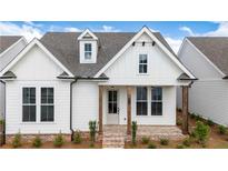 Charming white farmhouse-style home with brick-paved porch and manicured landscaping enhancing its curb appeal at 515 Cottage Creek Dr, Cumming, GA 30040