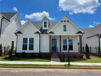 Charming white home featuring a landscaped yard, covered porch, and a combination of modern and traditional architectural elements at 515 Cottage Creek Dr, Cumming, GA 30040