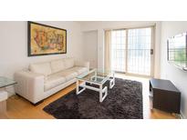 Bright living room with hardwood floors, white couch, and access to a balcony at 199 14Th Ne St # 1209, Atlanta, GA 30309