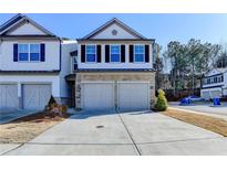 Two-story townhome with stone and white siding, three-car garage, and landscaping at 2732 Rigby Ln, Duluth, GA 30097
