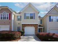 Charming two-story townhome featuring a one car garage, gray shutters, and manicured shrubs at 5665 Terremont Cir, Norcross, GA 30093