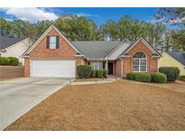 Charming one-story brick home featuring manicured landscaping, a two-car garage, and a welcoming front lawn at 661 Towering Pine Se Trl, Lawrenceville, GA 30045