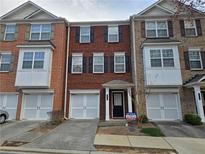 Brick townhome featuring a one car garage, symmetrical windows and professionally maintained landscaping at 2192 Landing Walk Dr, Duluth, GA 30097