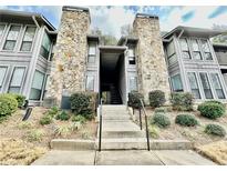 View of the condo's exterior featuring stone accents and landscaping at 4079 Woodridge Way, Tucker, GA 30084