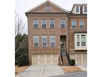 Brick three-story townhome with two-car garage and front steps at 1048 Township Sq, Alpharetta, GA 30022