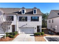 Two-story townhome with white brick exterior, two-car garage, and landscaping at 3532 Amarath Ter, Duluth, GA 30096