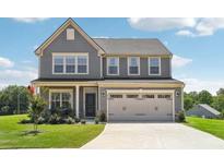 Two-story house with gray siding, beige garage, and manicured lawn at 864 Maduro Way, Mcdonough, GA 30253