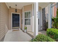 Welcoming front entrance with black door, beige siding, manicured landscaping, and well-lit porch at 2555 Flat Shoals Rd, Atlanta, GA 30349