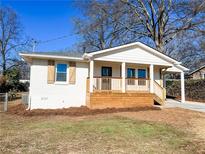 Charming white cottage with a front porch, new landscaping, and a driveway at 1045 Ridgecrest Se Dr, Smyrna, GA 30080