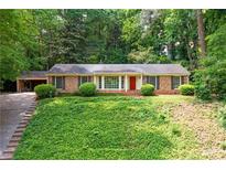 Charming brick home featuring lush green ground cover and a classic red front door at 6550 Bridgewood Valley Rd, Atlanta, GA 30328