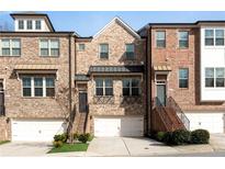 Charming brick townhome featuring a two-car garage, multiple windows and landscaped entryway at 4139 Torver Ln, Atlanta, GA 30341