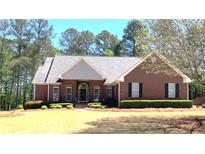 Beautiful brick home featuring a well-manicured lawn and a classic design with dark shutters and arched entry at 517 Mary Margaret Walk, Loganville, GA 30052