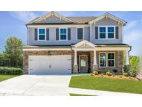 Charming two-story home with stone accents, covered porch, attached two car garage, and well-manicured lawn at 722 Crossroad Ct, Powder Springs, GA 30127