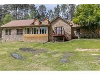 Stone house with a sunroom and deck, set on a spacious lawn at 1907 Old Loganville Rd, Loganville, GA 30052