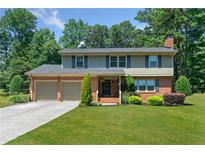 Charming two-story brick home with a manicured lawn, mature trees, and an attached two-car garage at 647 Shannon Green Cir, Mableton, GA 30126