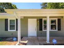 Inviting home exterior featuring a white front door with black shutters and security system at 780 Navajo Trl, Covington, GA 30016