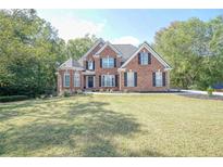 Brick two-story house with a large front yard and mature trees at 1213 Blue Springs Dr, Loganville, GA 30052