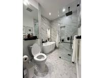 Modern bathroom with white marble walls, a luxurious soaking tub, and a glass-enclosed shower at 220 Renaissance Pkwy # 1203, Atlanta, GA 30308