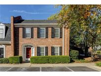 Brick townhouse with red door, shutters, and well-manicured landscaping at 14 Newport Nw Pl, Atlanta, GA 30318