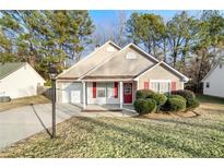 Tan house with red door, landscaping, and a driveway at 191 Misty Ridge Trl, Stockbridge, GA 30281