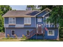 Charming two-story home with blue siding, updated windows, wooden deck, and a well-maintained lawn at 1469 Harmony Grove Church Rd, Auburn, GA 30011