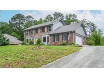 Beautiful two-story brick home with an attached garage and a well-manicured front lawn with mature trees at 830 Montego Sw Way, Lilburn, GA 30047