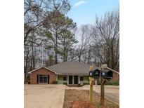 Charming single-story home with brick and olive green accents, surrounded by mature trees and a spacious driveway at 1119 Summer Brook Rd, Atlanta, GA 30349