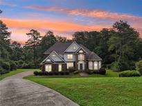 Brick house with a large yard, long driveway and sunset in the background at 3071 N Tower Ne Way, Conyers, GA 30012