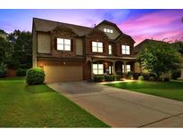 Two-story home showcases a beautiful brick and tan siding, an attached garage, and a well-manicured lawn at 4850 Wilshire Xing, Cumming, GA 30040